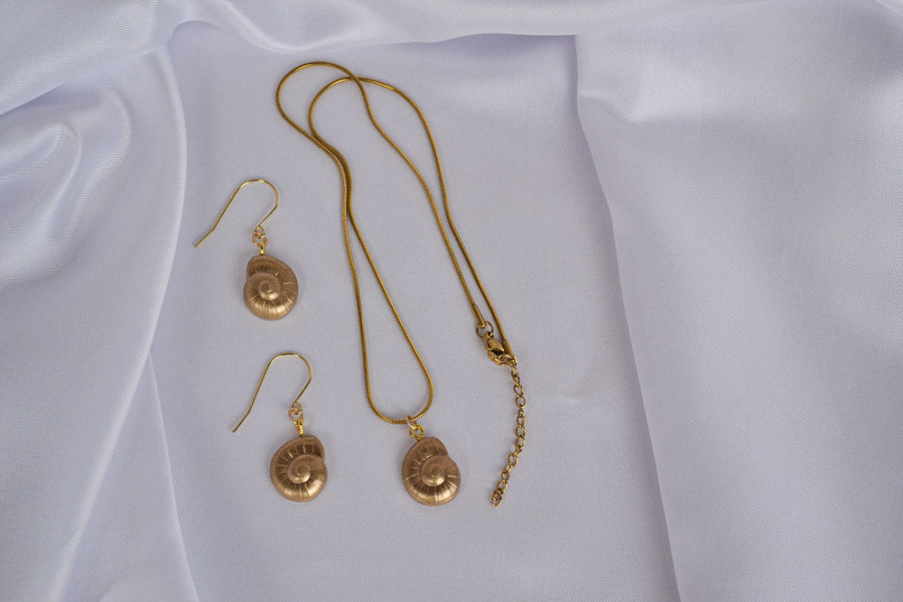 Schmuckset in Gold mit Muschel Anhängern auf weißem Stoff