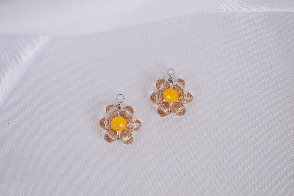 Nahaufnahme von zwei Anhängern aus glänzenden Glasperlen, handgemacht und geformt zu einer Blume