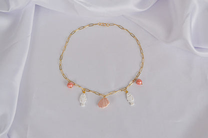 Charm Kette mit Fischen, Muschel und Perlen auf weißem Stoff