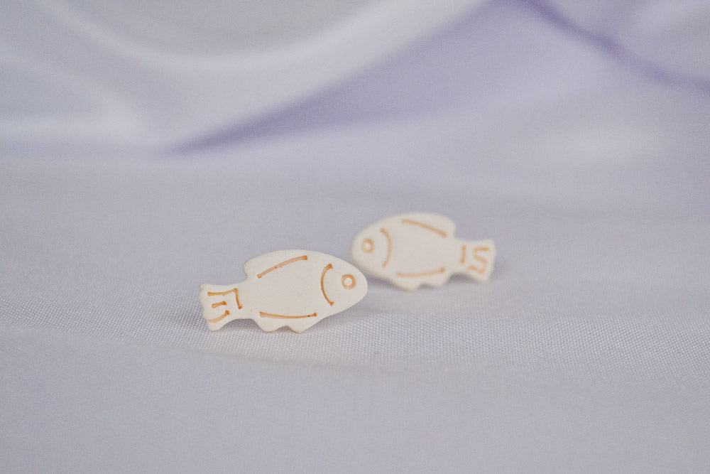 Beige Fisch Ohrstecker auf einem weißen Tuch