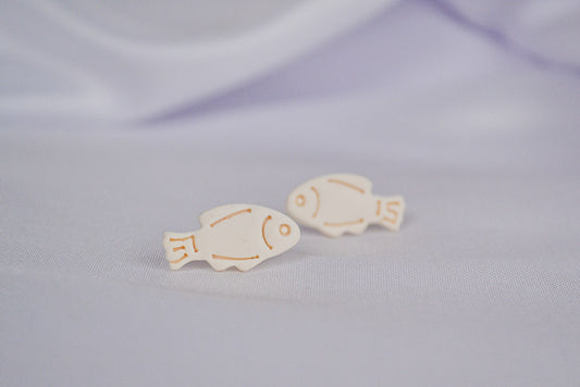 Beige Fisch Ohrstecker auf einem weißen Tuch