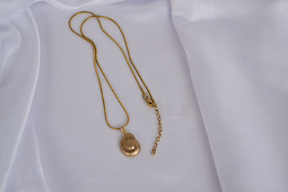 Halskette mit Muschel Charm in Gold auf weißem Stoff