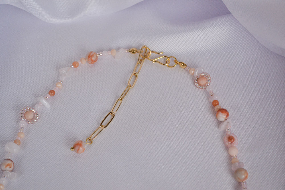 Edelsteinkette auf weißem Tuch in Nahaufnahme, zu sehen sind der S-Verschluss und eine Verlängerungskette