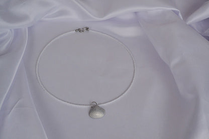 Perlenkette in weiß mit silber Muschel auf weißem Stoff