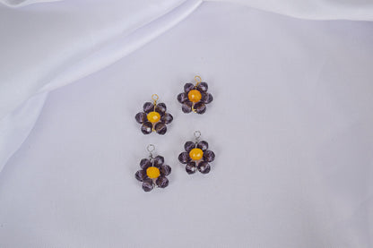 zwei Anhängern aus glänzenden Glasperlen in Violett und Gelb, handgemacht und geformt zu einer Blume